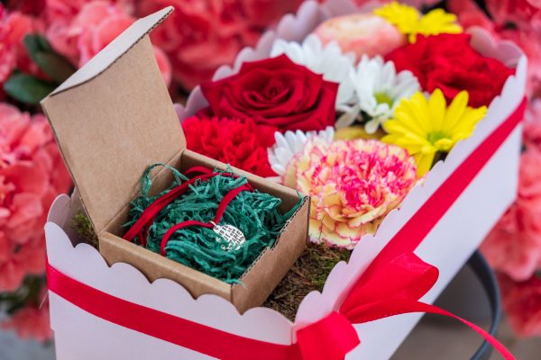composizione in spugna di fiori freschi e gioiello in argento in scatola rosa con coperchio trasparente