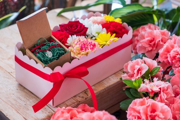 composizione in spugna di fiori freschi e gioiello in argento in scatola rosa con coperchio trasparente