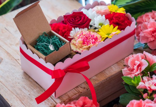 composizione in spugna di fiori freschi e gioiello in argento in scatola rosa con coperchio trasparente