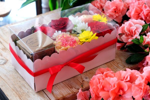 composizione in spugna di fiori freschi e gioiello in argento in scatola rosa con coperchio trasparente